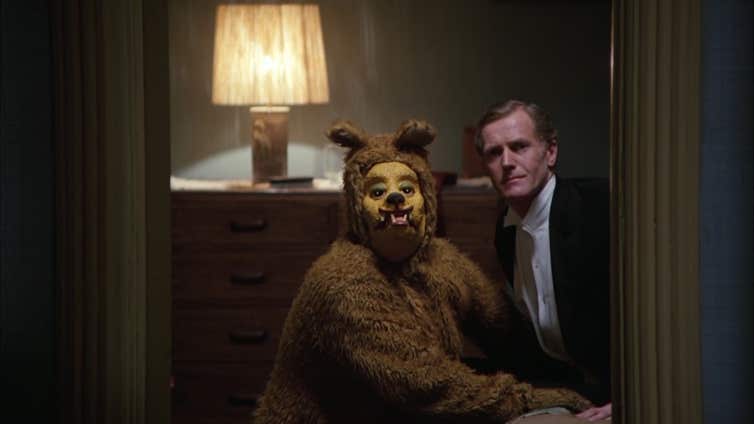 A man in a bear (?) costume in a sexual encounter with another man.